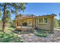 Wooden deck with pergola provides a cozy outdoor living space in the landscaped backyard at 29551 Dorothy Rd, Evergreen, CO 80439
