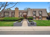 Charming home featuring unique wood siding, a brick chimney, and well-maintained landscaping at 4032 S Olive St, Denver, CO 80237