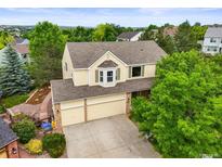 Two-story home boasts a three-car garage and bay window, nestled among lush green trees and landscaped yard at 6364 S Walden Ct, Aurora, CO 80016