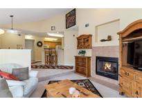 Inviting living room featuring a fireplace, wooden accents, and open access to the kitchen at 6001 S Yosemite St # B203, Greenwood Village, CO 80111