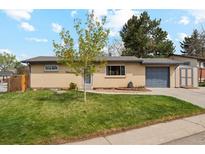 Charming single-story brick home featuring a well-manicured lawn, mature tree and an attached garage at 320 Orion St, Golden, CO 80401