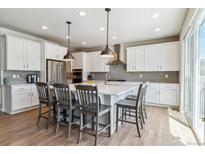 Open-concept kitchen with a center island, stainless steel appliances, and barstool seating, perfect for entertaining at 7240 S White Crow Way, Aurora, CO 80016