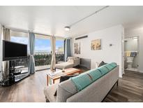 Bright living room featuring hardwood floors, a balcony with views, and comfortable seating at 1020 15Th St # 12C, Denver, CO 80202