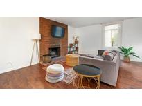 Bright living room features wood floors, a brick fireplace with TV, and neutral colored furniture at 3341 S Monaco Pkwy # A, Denver, CO 80222