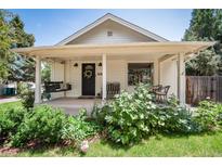 Charming covered front porch with a swing, seating, and beautifully landscaped yard at 6192 S Pennsylvania St, Centennial, CO 80121