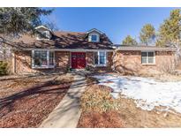 Brick ranch home with red door and landscaped yard at 5221 W Rowland Pl, Littleton, CO 80128