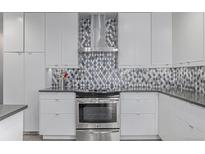 Modern kitchen features white cabinets, stainless steel appliances, and gray diamond patterned backsplash at 482 W Caley Ave, Littleton, CO 80120