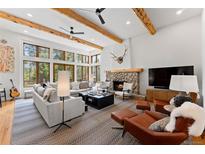 Spacious living room with beamed ceilings, large windows, stone fireplace, and comfortable seating at 110 Windwood Cir, Breckenridge, CO 80424