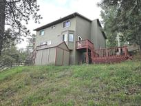 A serene home exterior with a deck, small shed, and staircase against a grassy backdrop at 29788 Aspen Ln, Evergreen, CO 80439
