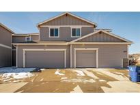 Two-story home featuring a gray exterior, two-car garage, and well-maintained lawn with natural light and clear skies at 6105 Verbena Ct # 103, Erie, CO 80516