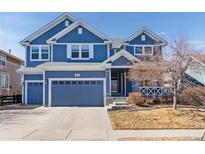 Charming two-story home featuring blue siding, white trim, an attached two-car garage, and well-maintained landscaping at 1114 Lasnik St, Erie, CO 80516