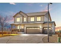 Charming two-story home featuring a three-car garage, covered porch, and beautiful exterior lighting at 16525 Sanford St, Mead, CO 80542