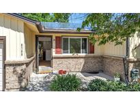 Charming home entrance with solar panels, brick accents, and an open doorway, inviting guests inside at 8705 W 86Th Dr, Arvada, CO 80005