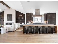 A modern kitchen features a central island with bar seating, a sleek range hood, and hardwood floors at 3112 Braun Ct, Golden, CO 80401