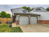 Charming townhouse with two-car garage, red brick accents and lush green lawn at 12556 Elm St, Thornton, CO 80241