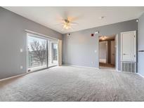 Spacious living room with sliding glass doors to a balcony and neutral color scheme at 15700 E Jamison Dr # 2-204, Englewood, CO 80112