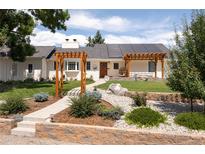 Charming ranch-style home featuring solar panels, a landscaped front yard, and inviting pergola entrances at 14117 W 58Th Pl, Arvada, CO 80004