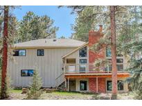 Charming home featuring a red brick chimney and a lovely deck surrounded by lush greenery and mature trees at 8795 Rudd Rd, Evergreen, CO 80439