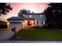Charming two-story home with a well-maintained lawn and an attached garage, showcased at sunset at 7431 Webster St, Arvada, CO 80003