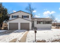 Charming two-story home with a two car garage and snow covered yard at 6190 W Canyon Ave, Littleton, CO 80128