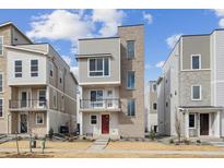 Striking three-story home featuring modern architecture, a small balcony, and a vibrant red front door at 1255 Penner Dr, Erie, CO 80026
