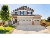 Charming two-story home featuring a three car garage, well-manicured lawn, and inviting front porch at 10978 Ashurst Ln, Highlands Ranch, CO 80130