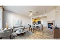 Open-concept living room features a fireplace, dining area and adjacent kitchen space, creating a warm, inviting atmosphere at 16047 E Geddes Ln # 128, Aurora, CO 80016