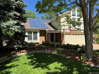 Charming home featuring solar panels, a brick facade, lush lawn, mature trees and beautiful landscaping at 8535 E Otero Cir, Centennial, CO 80112