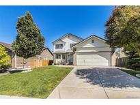 Two-story home boasts a well-manicured lawn, mature trees, and a two-car garage at 21924 E Lake Ave, Aurora, CO 80015
