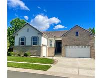 Charming two-story home with a well-manicured lawn, brick accents, and attached two car garage at 4545 Oxbow Dr, Brighton, CO 80601