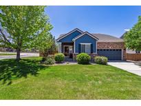 Charming blue and brick home with a well-manicured lawn, mature trees, and inviting curb appeal at 2670 E 136Th Pl, Thornton, CO 80602