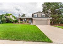 Charming two-story home featuring a brick facade, manicured lawn, and a two-car attached garage at 8588 S Woody Way, Highlands Ranch, CO 80126