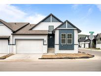 Charming two-story home featuring a white exterior, dark blue accents, an attached two-car garage and an unfinished lawn at 8277 S Quail St, Littleton, CO 80127