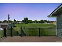 Relaxing back deck area overlooking a grassy field with white fence and barn at 15545 Lipan St, Broomfield, CO 80023
