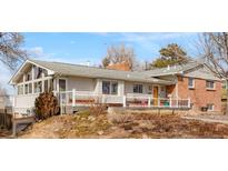 Charming single-story home with a brick facade, gray siding, and inviting front porch at 11845 W 30Th Pl, Lakewood, CO 80215