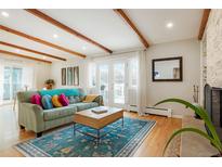 Bright living room with wood beams, hardwood floors, and a cozy fireplace at 11845 W 30Th Pl, Lakewood, CO 80215