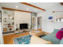 Inviting living room with a stacked stone fireplace, exposed beams, and stylish decor at 11845 W 30Th Pl, Lakewood, CO 80215