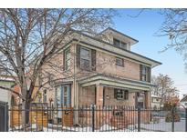 Charming brick home featuring a covered front porch, a well-kept yard and metal perimeter fence at 201 S Logan St, Denver, CO 80209