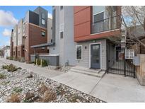 Modern townhouse with stone landscaping, gated front patio and muted gray, red and brown color palette at 2922 W 26Th Ave # 1, Denver, CO 80211