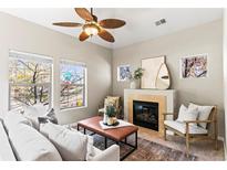 Cozy living room featuring a fireplace, ceiling fan, plush seating, and multiple bright windows at 9804 Martin Luther King Blvd, Denver, CO 80238