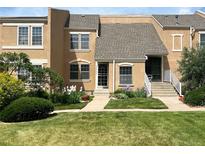 Charming townhome featuring manicured lawn, mature trees, and colorful flowerbeds enhancing the curb appeal at 13187 E Bethany Pl, Aurora, CO 80014