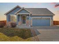 Charming blue single-Gathering home with stone accents, a well-kept lawn, and an attached two-car garage at 11324 Newport St, Thornton, CO 80233