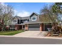 Charming two-story home with a gray exterior, brick accents, a well-manicured lawn, and a two-car garage at 5795 S Pagosa Way, Centennial, CO 80015