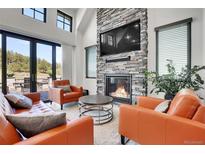 Inviting living room featuring a stone fireplace, comfortable seating, and large windows at 5166 Bear Mountain Dr, Evergreen, CO 80439
