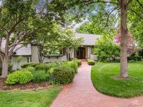 Charming single-story home featuring a lush front yard, brick pathway, and meticulously landscaped garden beds at 3975 S Cherry St, Cherry Hills Village, CO 80113