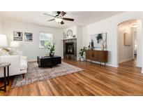 Bright living room features hardwood floors, a ceiling fan, and a stone fireplace at 4197 S Grant St, Englewood, CO 80113