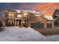 Two-story home with stone accents, a three-car garage, and a snow-covered front yard at 1480 Sterling Hill Ct, Castle Rock, CO 80104