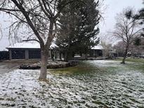 Charming single-story home featuring a well-manicured lawn and a three car garage, partially covered in snow at 8659 E Kenyon Ave, Denver, CO 80237