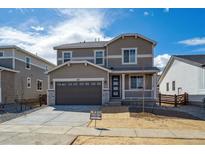 Two-story home featuring a two-car garage and covered porch, set against a bright blue sky with scattered clouds at 1312 Sienna Peak Cir, Erie, CO 80516