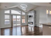 Bright living room with modern fireplace, mounted TV, hardwood floors, and balcony access at 14251 E 1St Dr # 308, Aurora, CO 80011